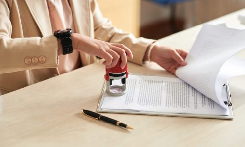 Businesswoman applying company seal to important documents